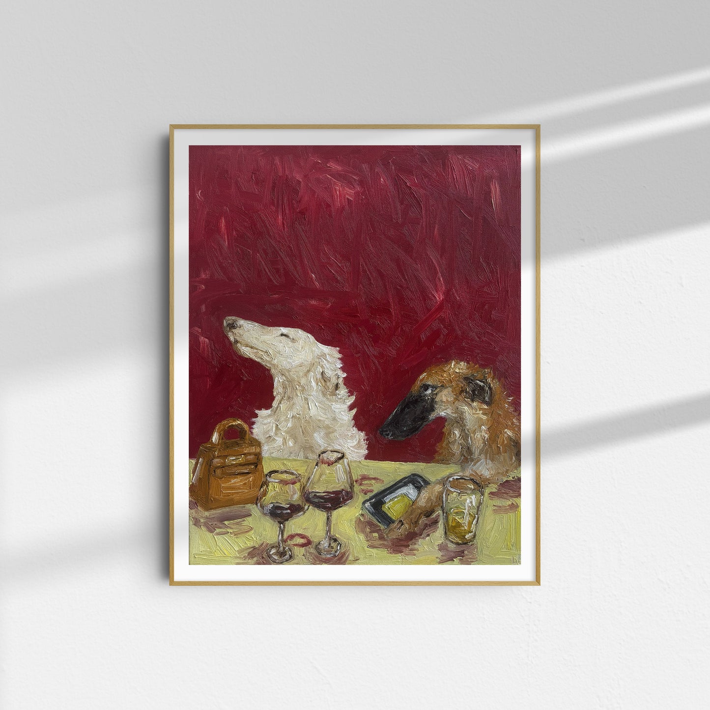 A framed limited edition art print titled "As If" by Leah Boyd, featuring two dogs sitting at a table with two glasses of wine, a handbag, a phone, and a glass of water against a deep red textured background.