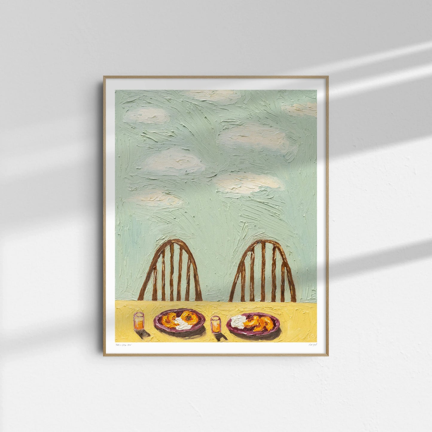 "Peaches & Cottage Cheese" by Leah Boyd is a framed oil on canvas depicting two empty wooden chairs at a table with peaches, cottage cheese, and drinks under a cloudy sky, sunlight casting shadows as it hangs on a white wall.