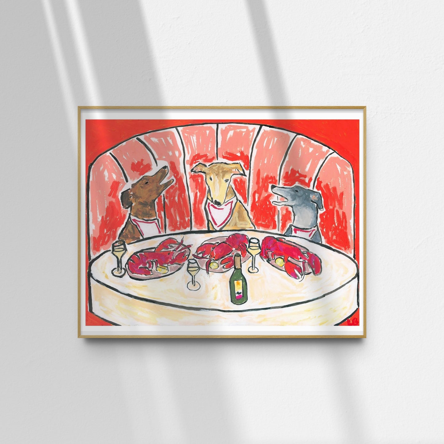 The "Lobsters & Yap" limited edition art print by Leah Boyd features three dogs in bibs at a round table with lobsters and wine, set against a red booth, sunlight casting shadows around the frame.