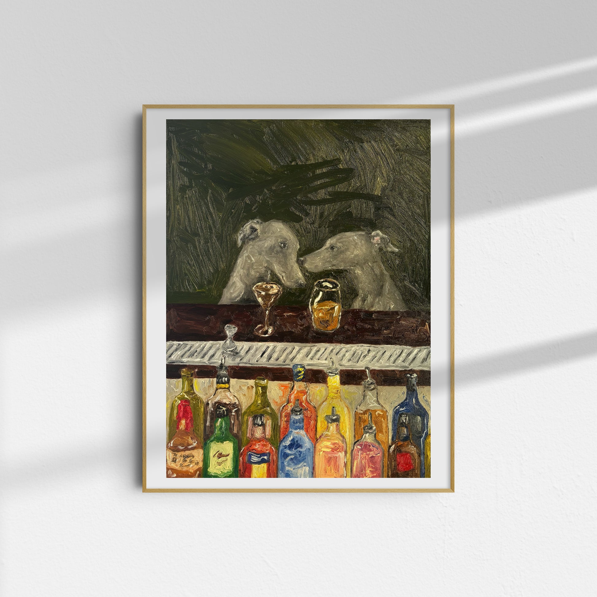 The Bar Scene [PRINT PREORDER] by Leah Boyd is a framed limited edition art print featuring two dogs at a bar with colorful bottles, set against an abstract dark background. The frame casts a shadow on the white wall.