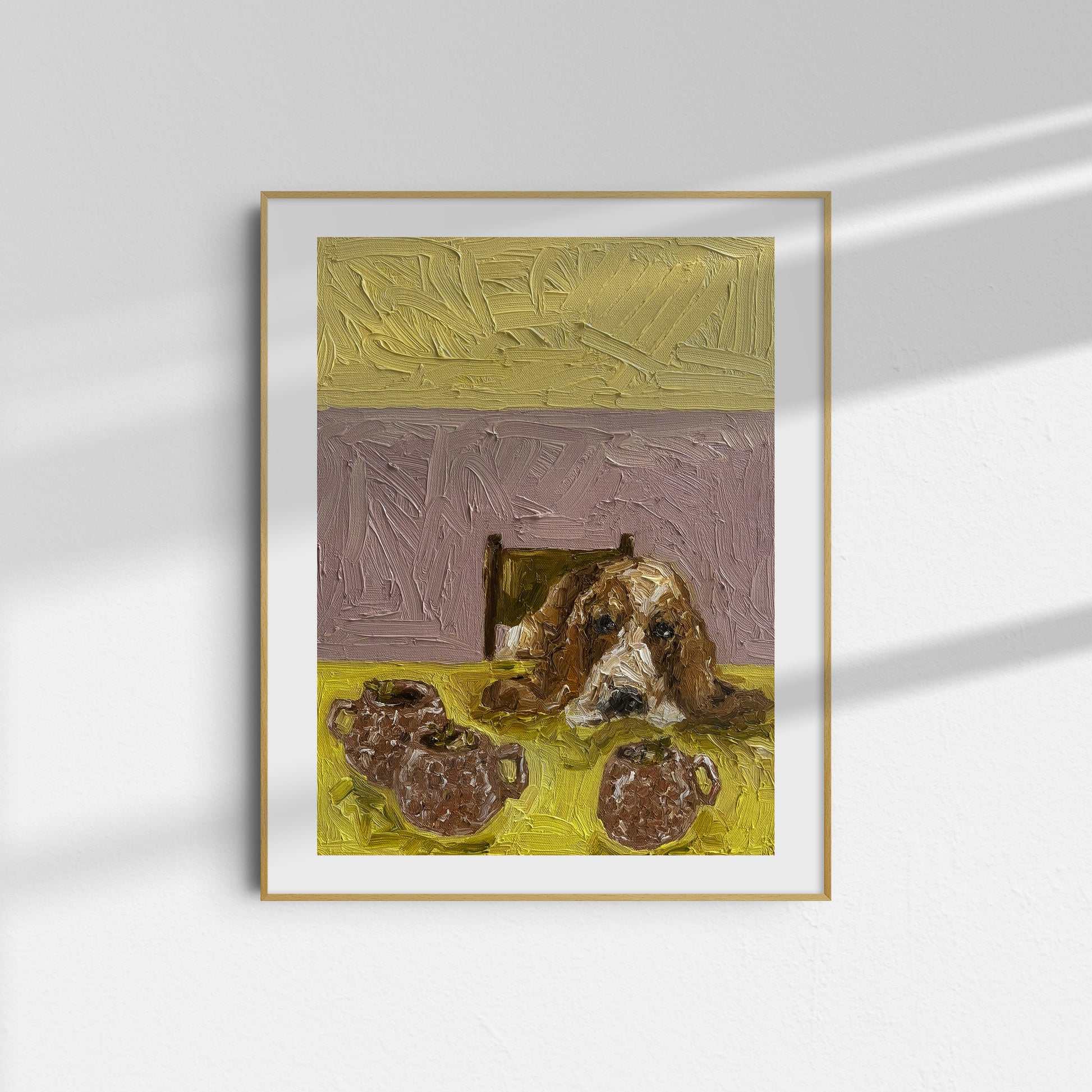 The Moscow Mule [PRINT PREORDER] by Leah Boyd is a framed limited edition Giclee print featuring a brown and white dog beside two pitchers, set against yellow and lavender hues, in a thin gold-bordered frame on a white wall.