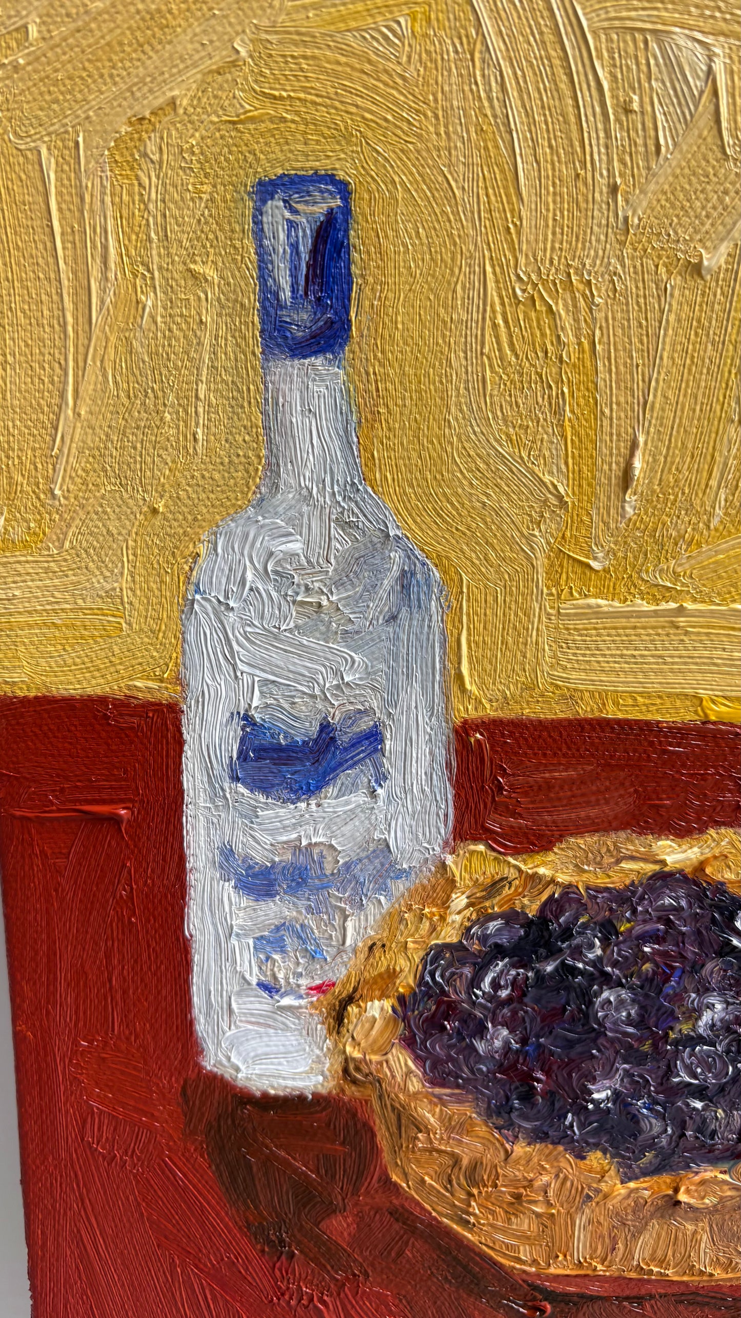 Leah Boyd’s “The Key to Pie Crust is Vodka” is an original oil painting featuring a clear bottle with a blue label next to a bowl of dark purple grapes on a vivid red and yellow textured background.