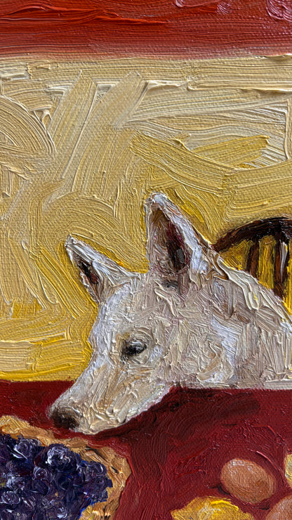 Close-up of Leah Boyd's "The Key to Pie Crust is Vodka," a signed oil painting of a white dog with pointed ears resting on a red table near grapes and a round object, set against a warm yellow-red background. Ideal for canvas art lovers.