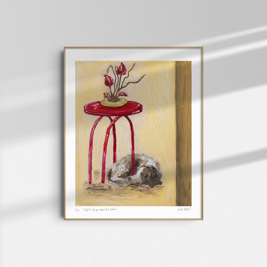 Leah Boyd’s "English Springer Spaniel & Ikebana" is a framed oil on canvas showing a red table with a potted plant and a curled-up dog below, bathed in sunlight with soft shadows on the light wall.