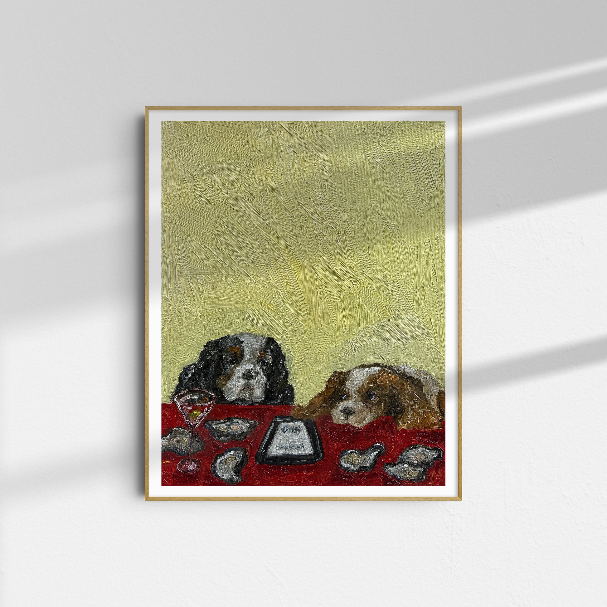 The Oysters, in Fact, Were Not $1 [PRINT PREORDER] by Leah Boyd is a framed limited edition art print featuring two dogs at a table with oysters and drinks on a red tablecloth against a textured yellow background.