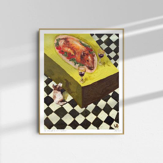 Leah Boyd's "Dinner for One no. 9: Pig Roast" is a limited edition framed Giclee art print showing a garnished roast pig, two glasses of wine, and a small dog on a checkered floor, displayed on a white wall.