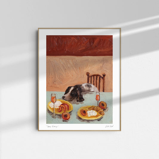 "Sunny Mornings" by Leah Boyd: a framed giclee print featuring a dog resting its head on a table with cottage cheese, peaches, and mimosas set before a warm-toned wall and wooden chair.