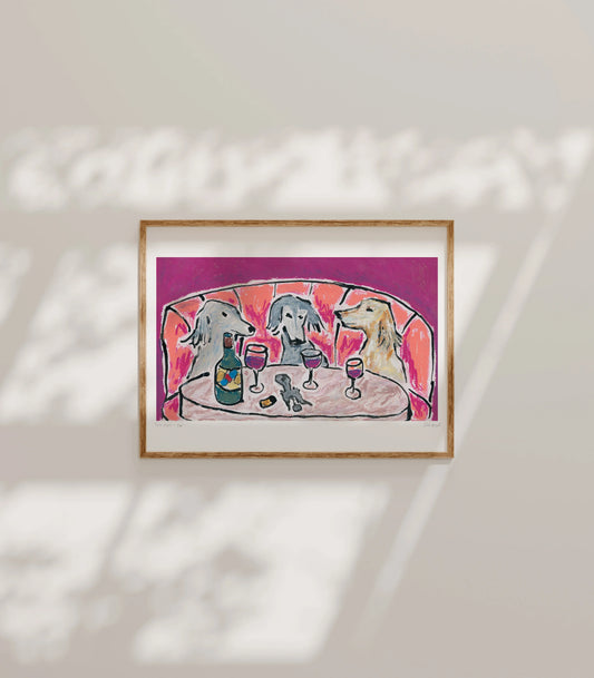 Leah Boyd's "Wine Night & Yap" is a framed giclee print on archival matte paper, showing three dogs with wine at a table against a red backdrop, sunlight casting gentle shadows in this charming open edition artwork.