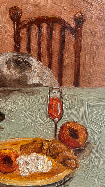 Leah Boyd’s “Sunny Mornings” is a textured original oil painting on canvas depicting a wooden chair, food on a plate, red drink in a glass, and two fruits on a table, all rendered with expressive brushstrokes.
